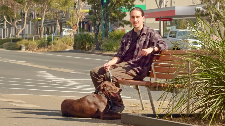 Tim McCartney sitting on a bench in Ringwood with his dog